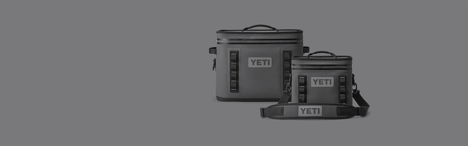 Two YETI coolers, one larger and one smaller, on a grey background.