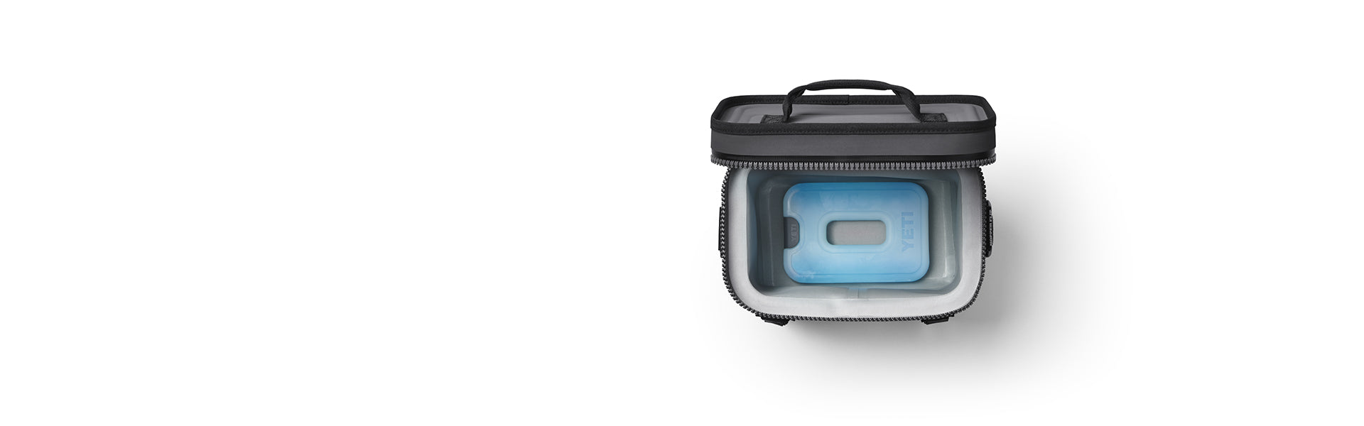 Black soft cooler, open with a YETI Ice block inside.