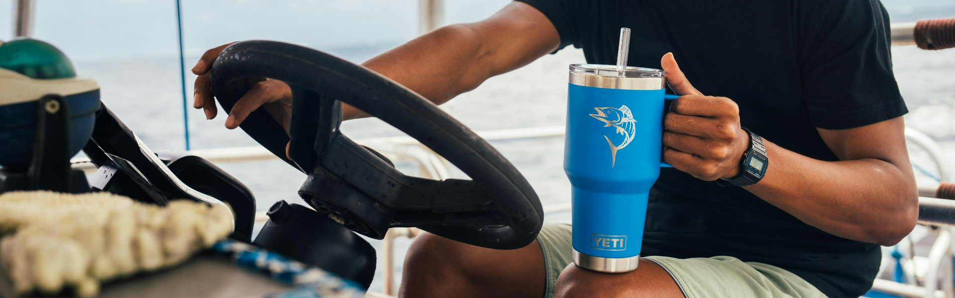 Person holding a blue tumbler with a steering wheel and vehicle interior in the background