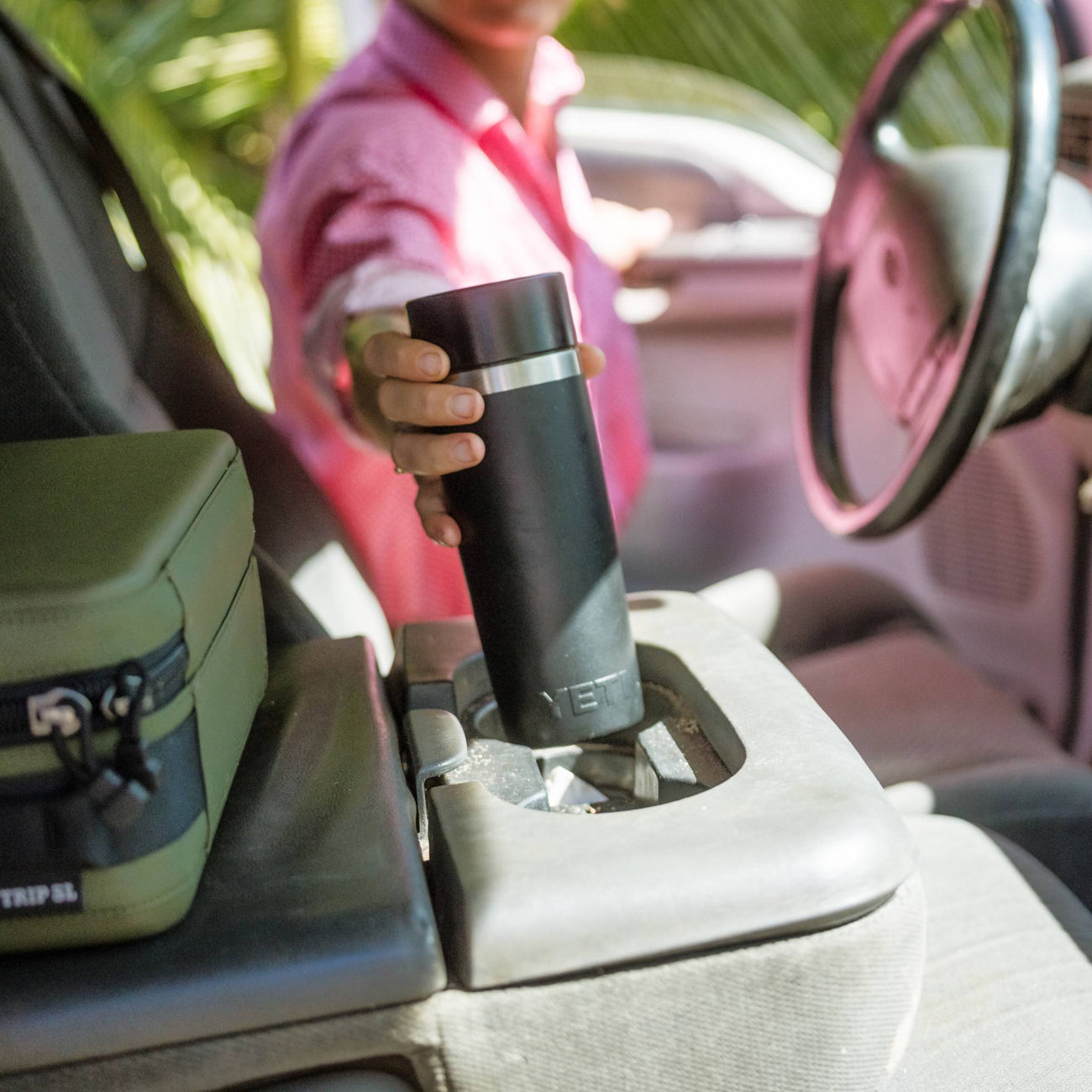 Person holding a yetti travel bottle in a car, with a focus on the product.