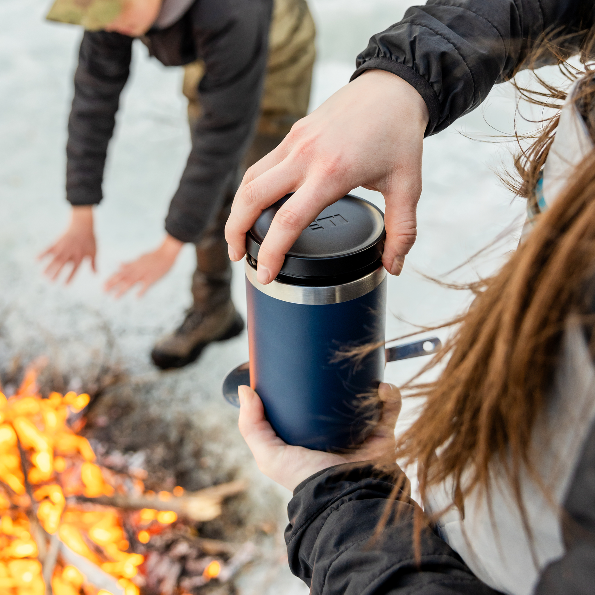 Person holding a YETI branded mug with coffee