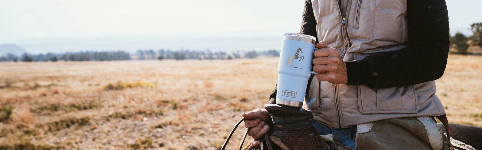 Person holding a yeti mug in a field