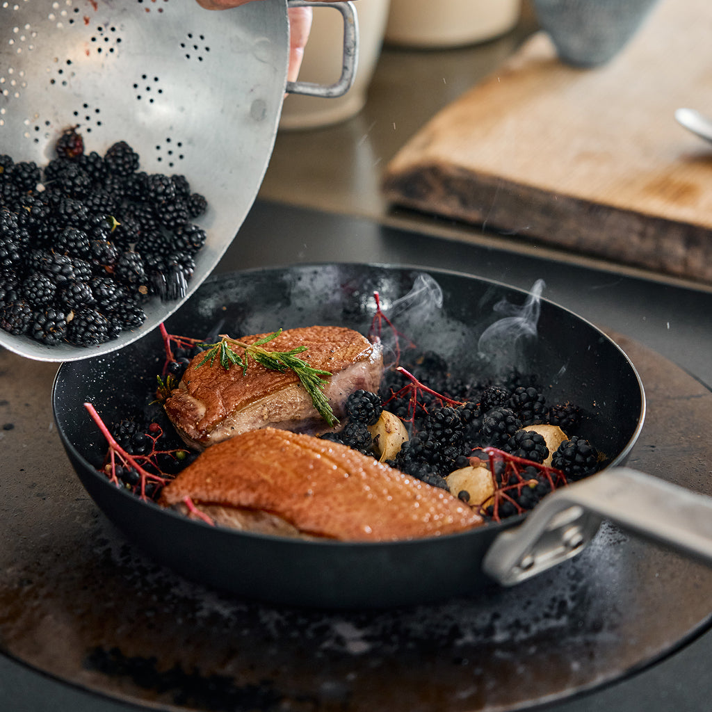 Searered meat with blackberries in a YETI pan on a stove