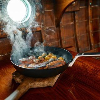 YETI frying pan with fish and vegetables on a wooden stove