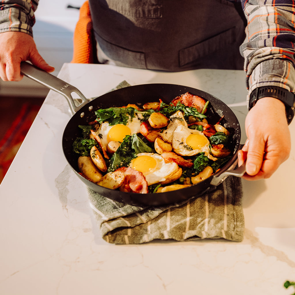 Person holding a YETI pan with a colorful breakfast dish on a kitchen counter