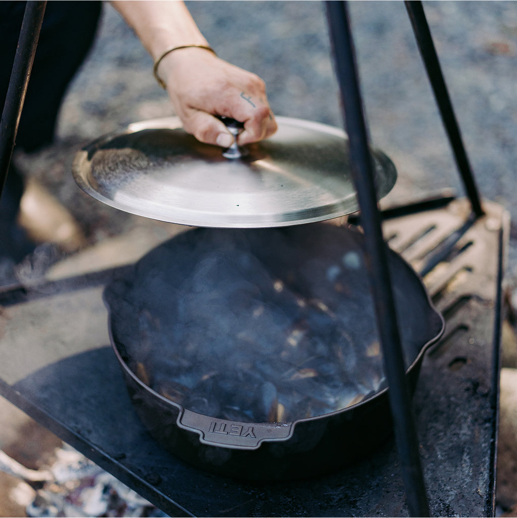 Hand closing a lid on a camping stove with a blurred natural background