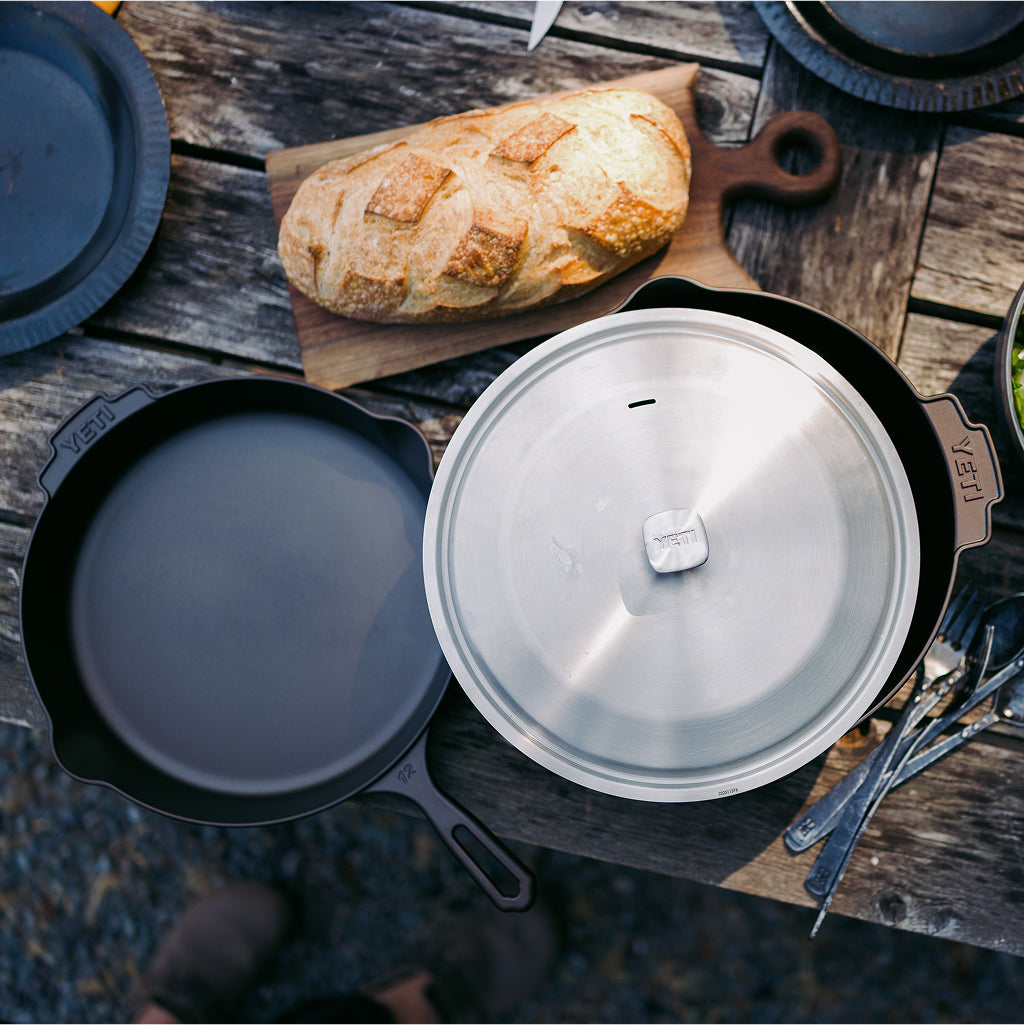 Cast iron cookware set on a wooden surface with bread
