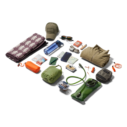 Collection of outdoor gear including a hat, sunglasses, camera, and various bags on a white background