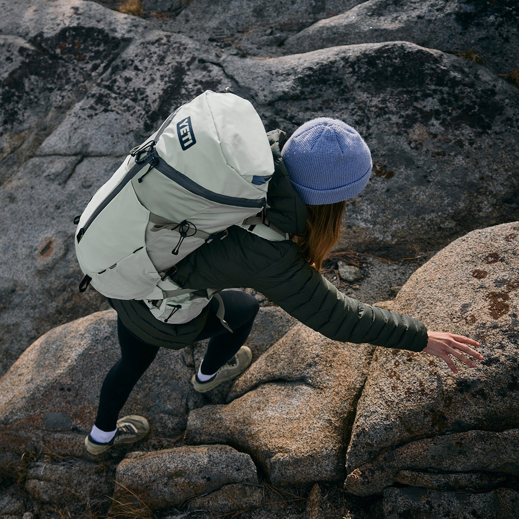 Person with a large hiking backpack climbing rocky terrain