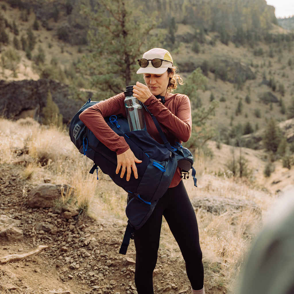 Person hiking in a mountainous area with a backpack and water bottle.