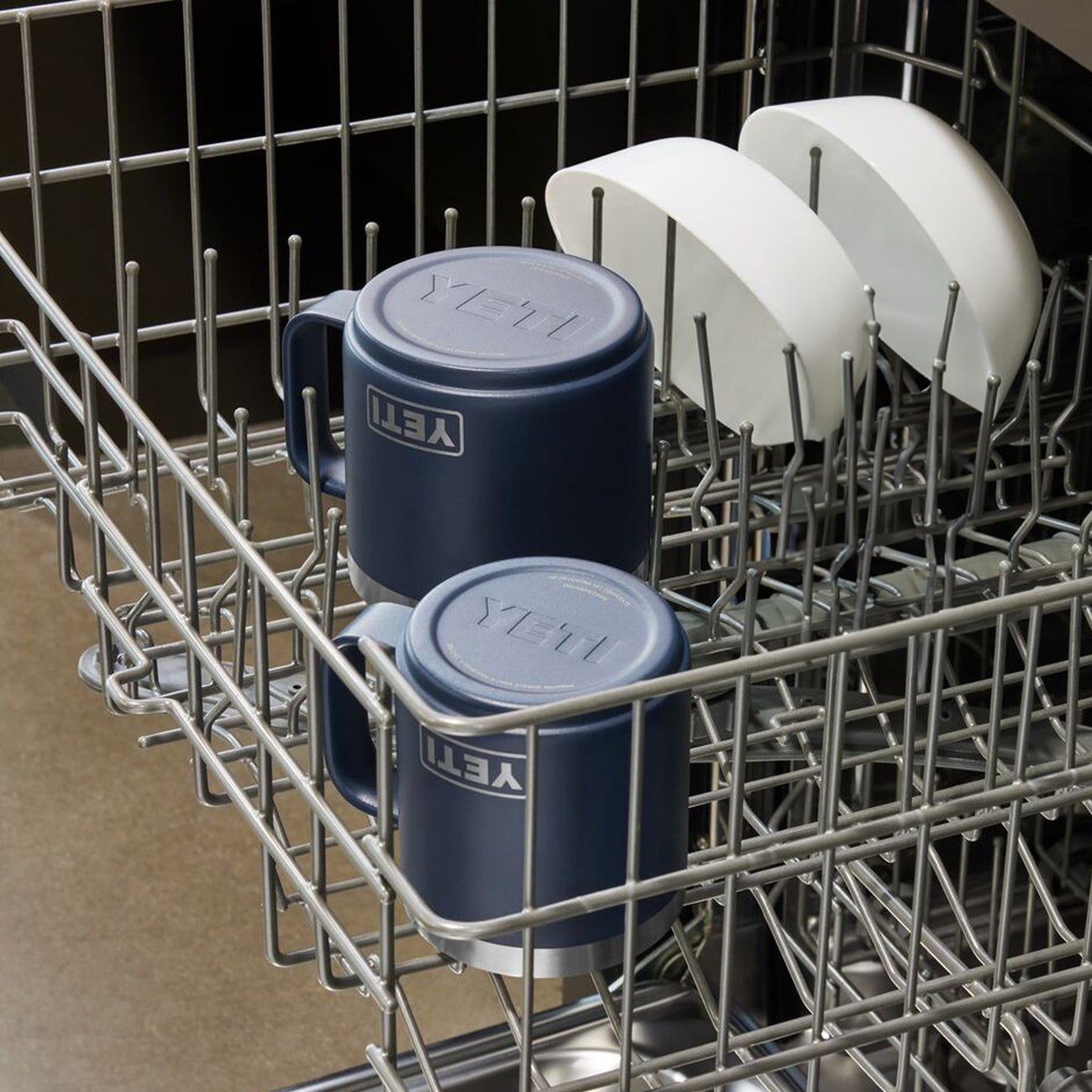 Blue mugs with 'YETI' logo in a dishwasher rack.