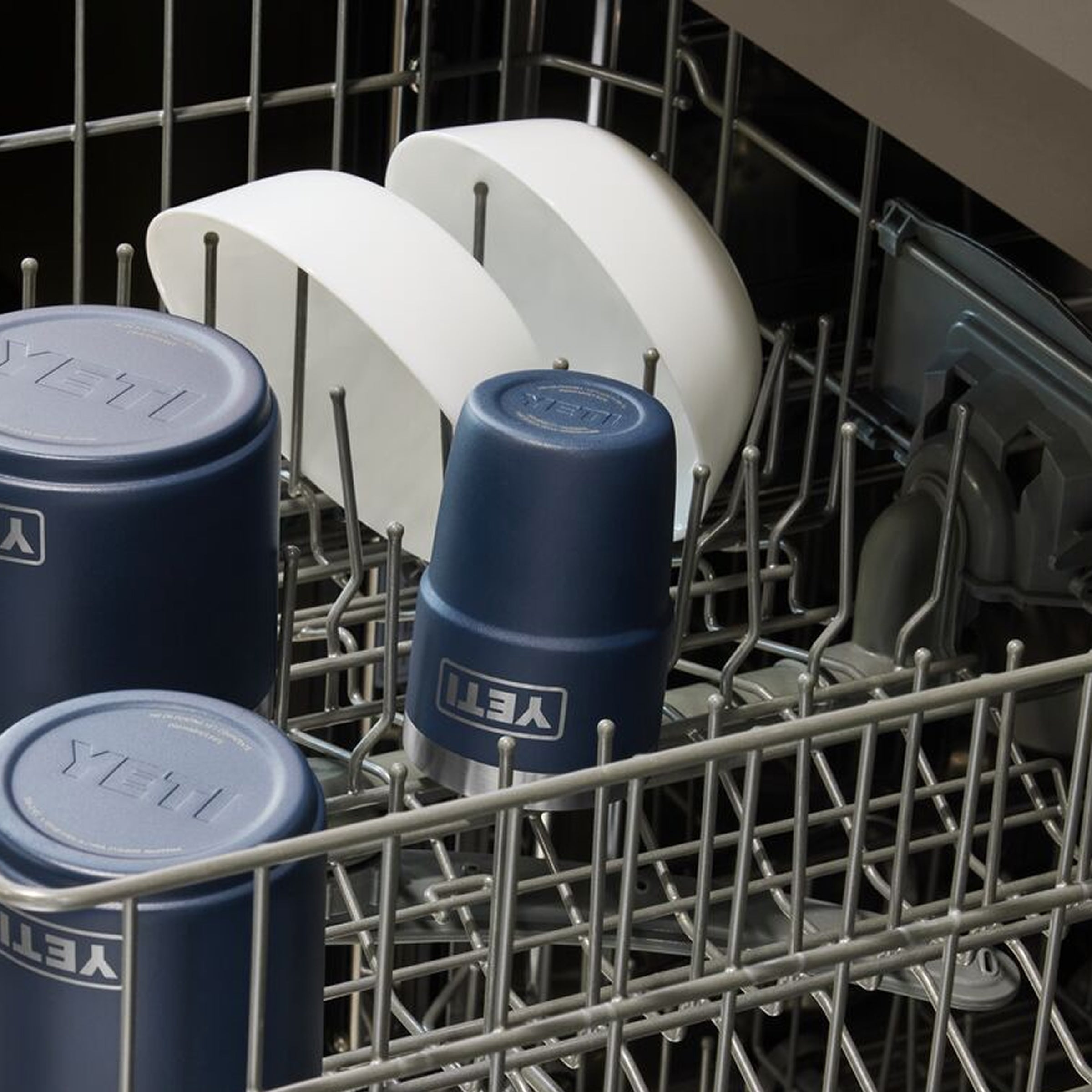 Blue mugs with 'YETI' logo in a dishwasher rack.