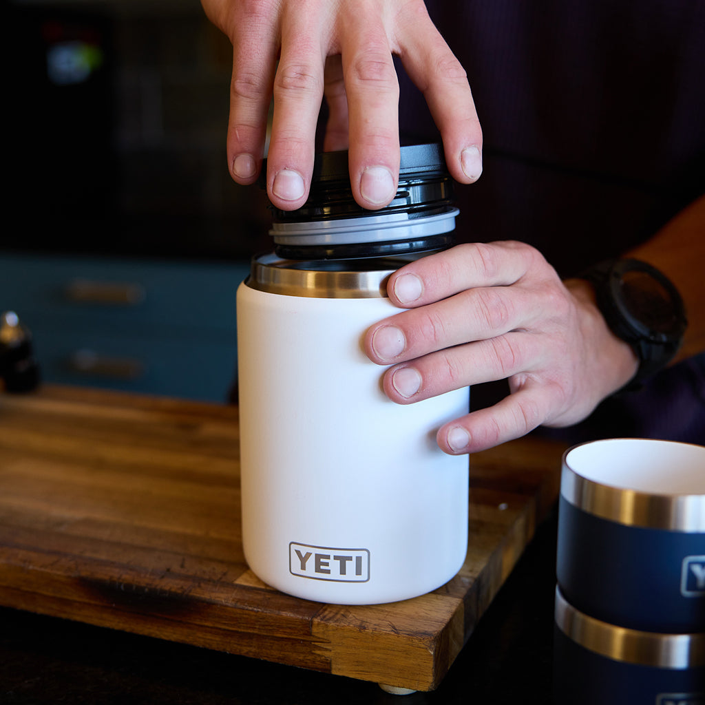 Person holding a YETI branded mug with coffee