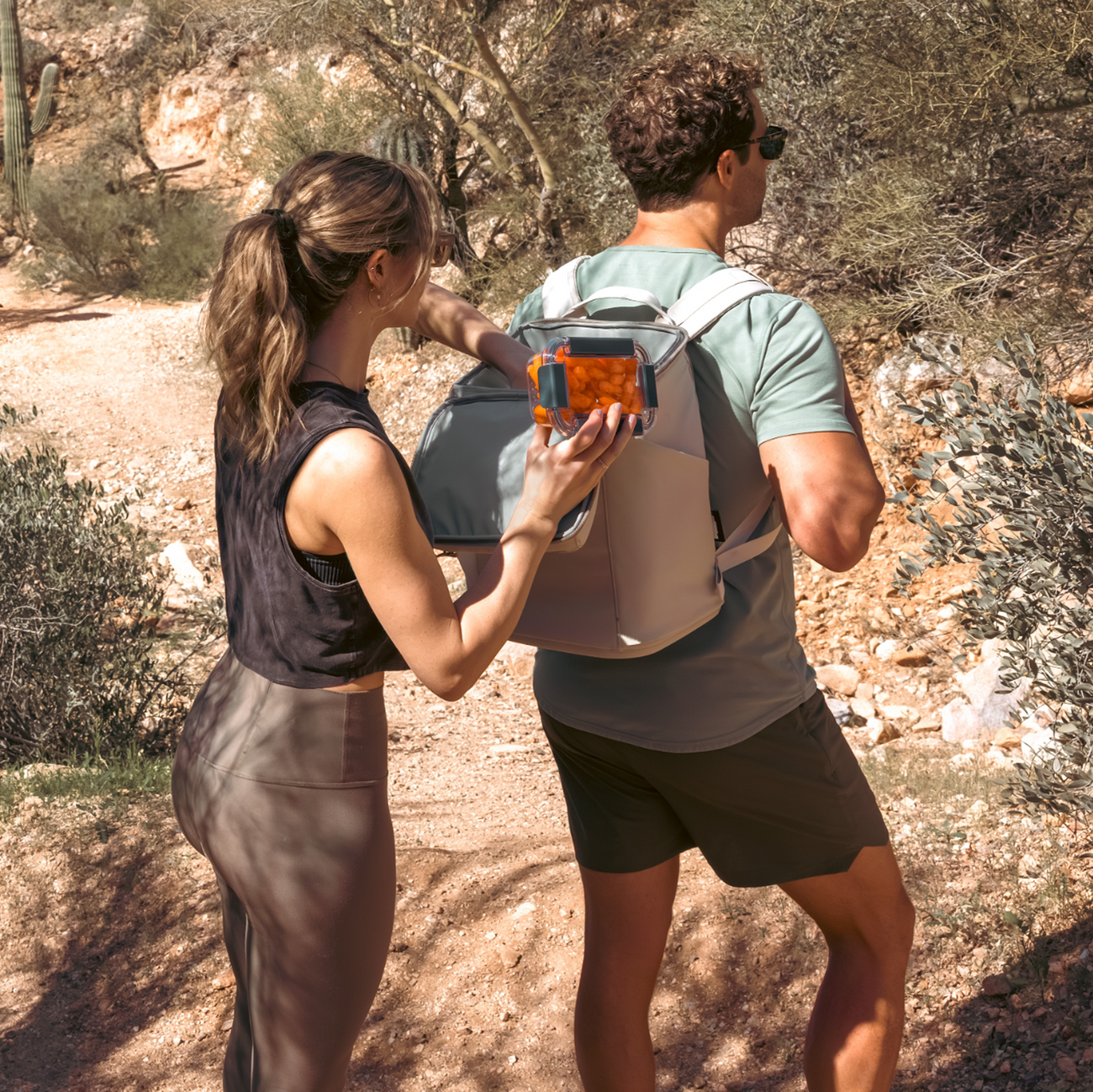 Two people outdoors, one holding a device and the other with a YETI backpack, in a natural setting.