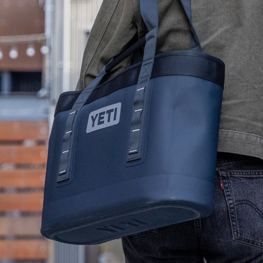 Person carrying a navy YETI camino bag outdoors.