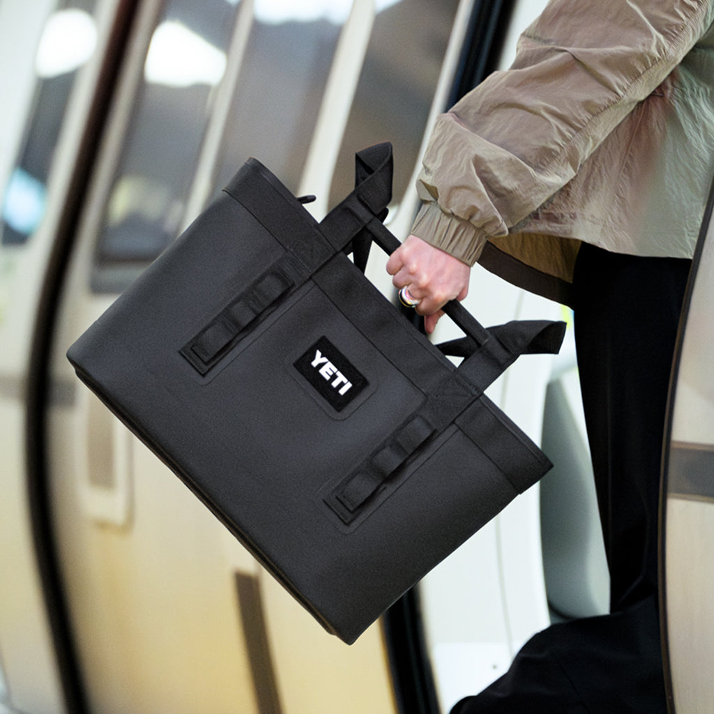 YETI Camino Zip tote bag, being held by handle on a train
