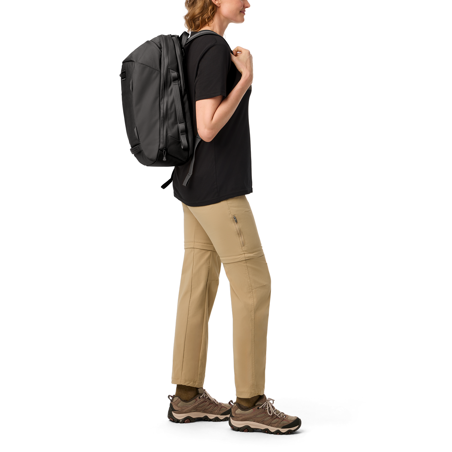 Person wearing a black backpack and beige trousers on a white background