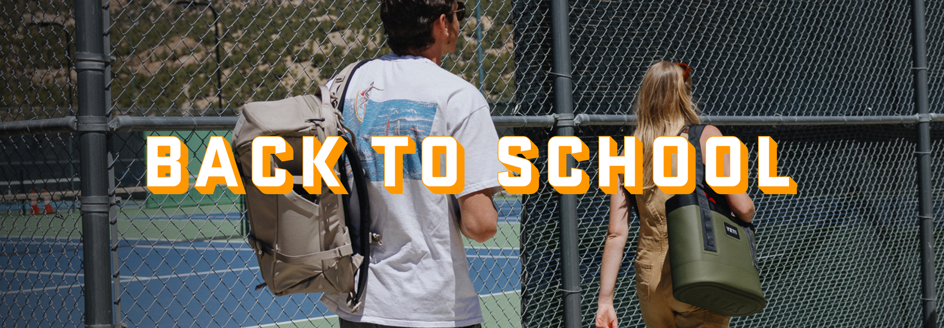 Two people with backpacks walking behind a chain-link fence with 'Back to School' text overlay.