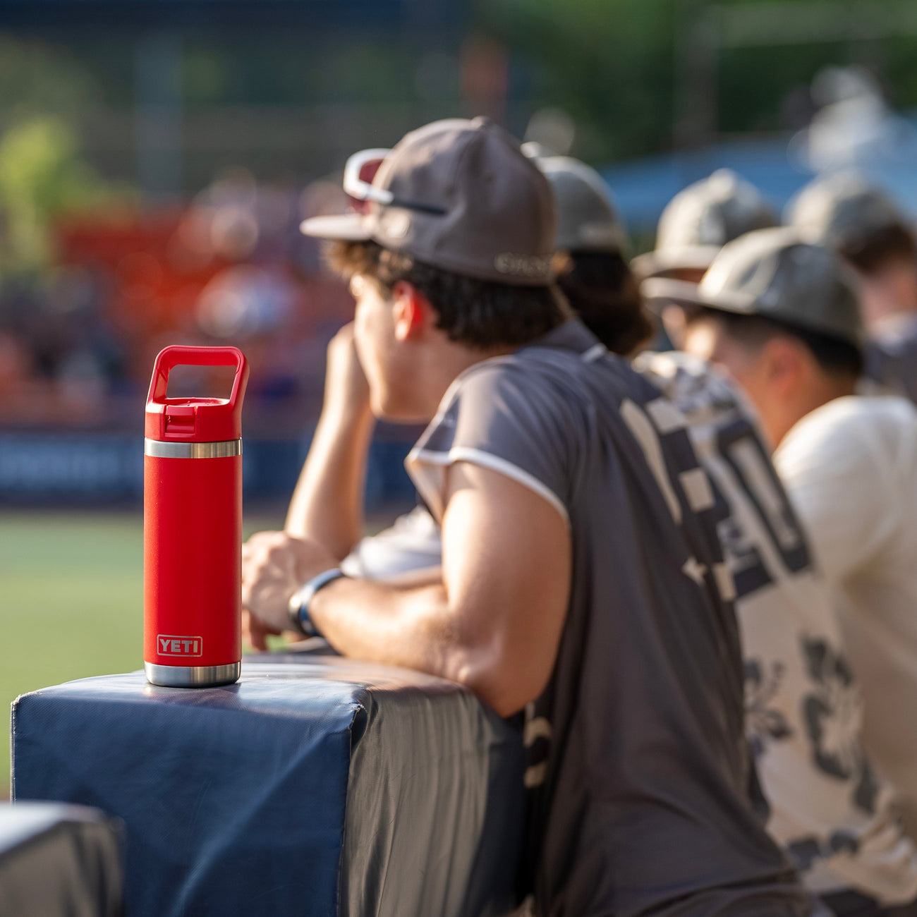 Red bottle on a table with people sitting around it, blurred background