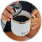 Person pouring coffee into a white mug with a logo on a wooden surface