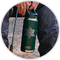 Person holding a green bottle with a custom design on a wooden surface