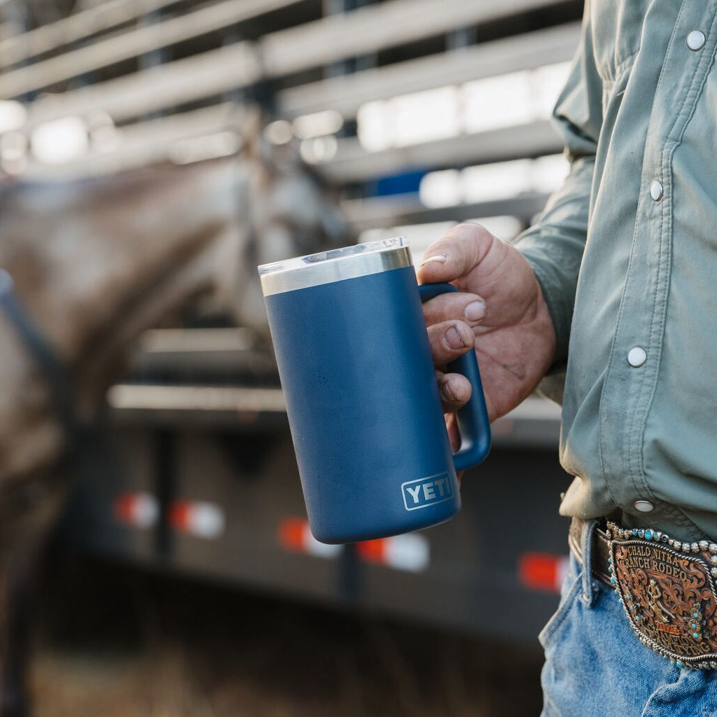 Person holding a blue mug with a horse in the background