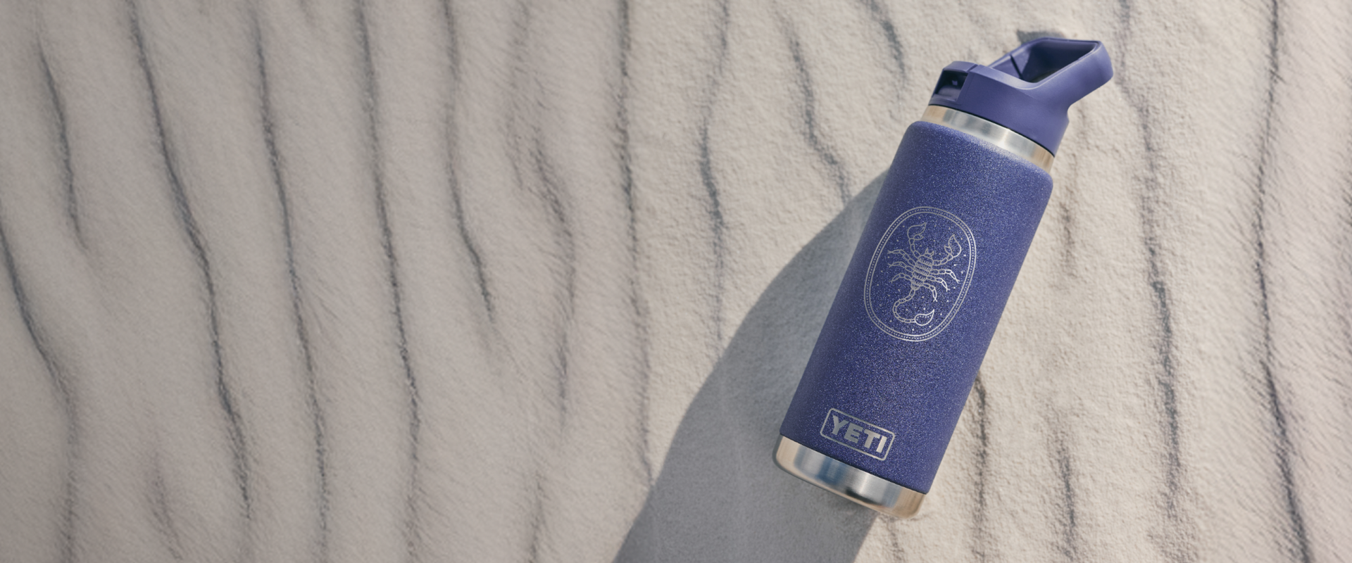 Purple YETI water bottle on a textured sand background