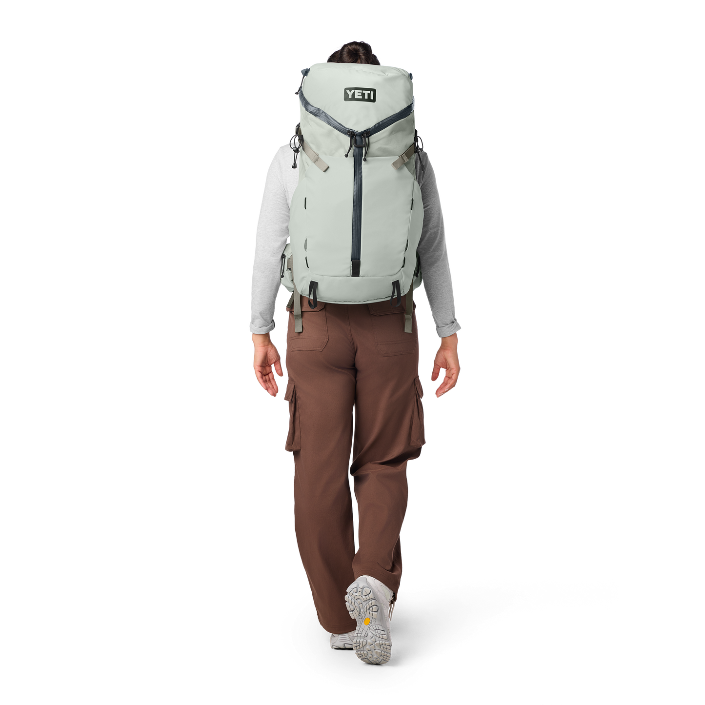 Person wearing a large backpack with 'YETI' branding on a white background