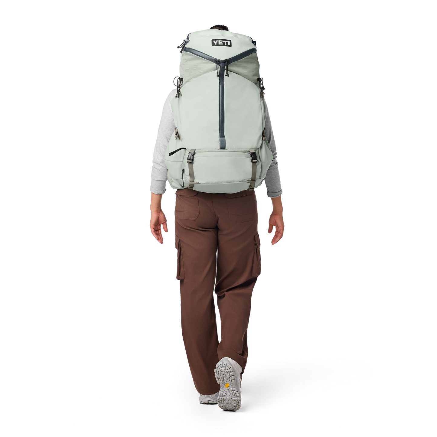 Person wearing a large green backpack with YETI logo on a white background