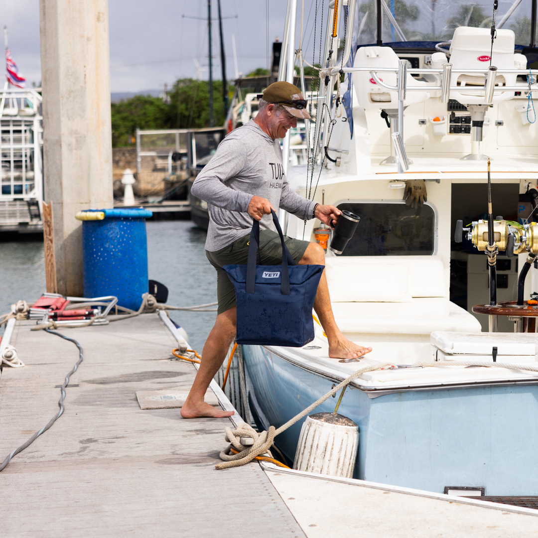 Man standing on a dock next to a boat with fishing equipment.